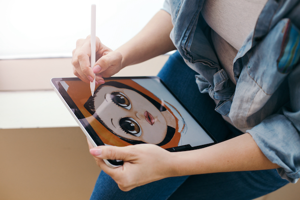 Woman artist painting drawing a anime style drawing on a digital tablet with a stylus