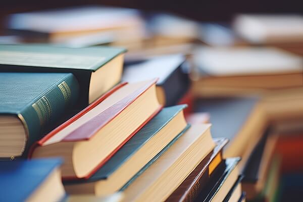 A large stack of multicolored covered books on a table