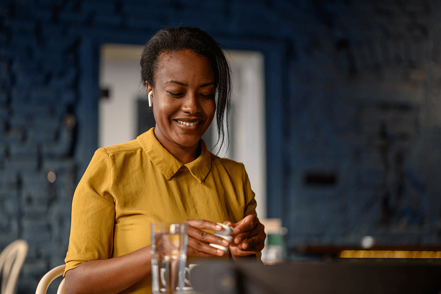 woman using airpods and a smartphone while sitting in a cafe