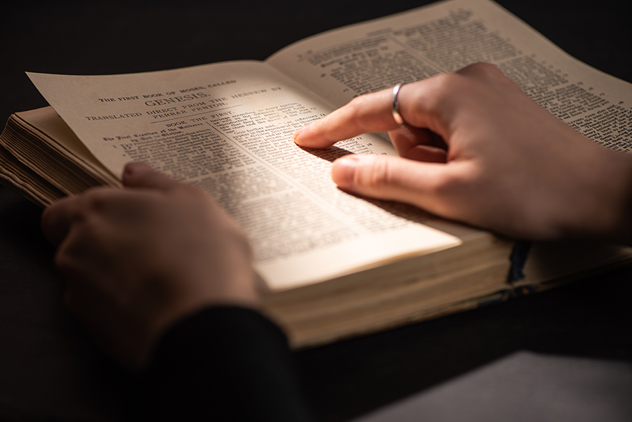 Cropped view of woman reading holy bible in dark with sunlight