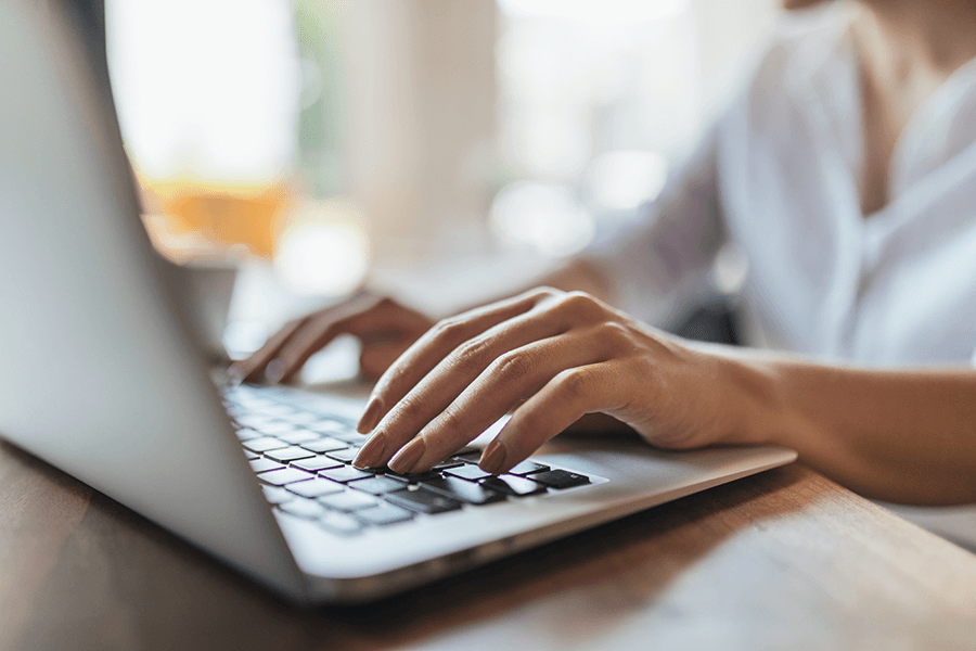 Writing-for-Your-Target-Audience A close up of a woman's hands typing on a laptop inside of a cafe