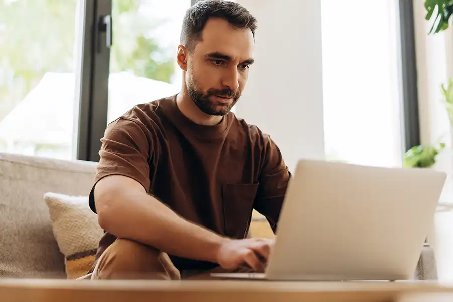 10 Social Media Content Ideas Every Author Should Try Middle-aged man sitting on his couch in is living room working on his laptop.