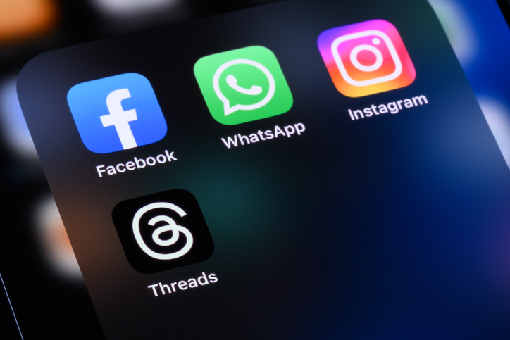 Meta Apps - Facebook, WhatsApp, Instagram, and Threads Handwritten sketch notes in a notebook on dark wooden table with a yellow coffee cup and black pen laying next to it