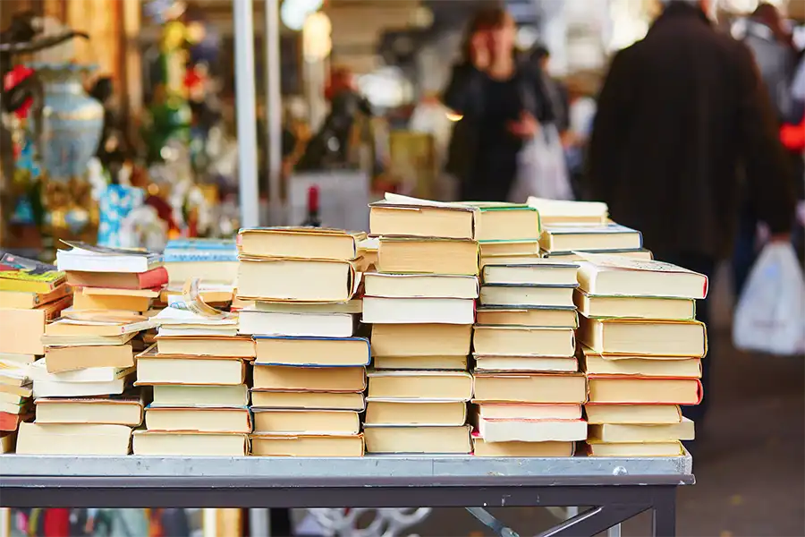 Large stack of colorful books resting on a table inside a bookstore