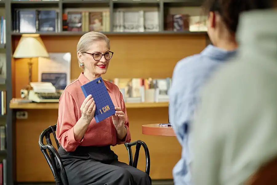A senior woman hosting a book signing event for her latest release