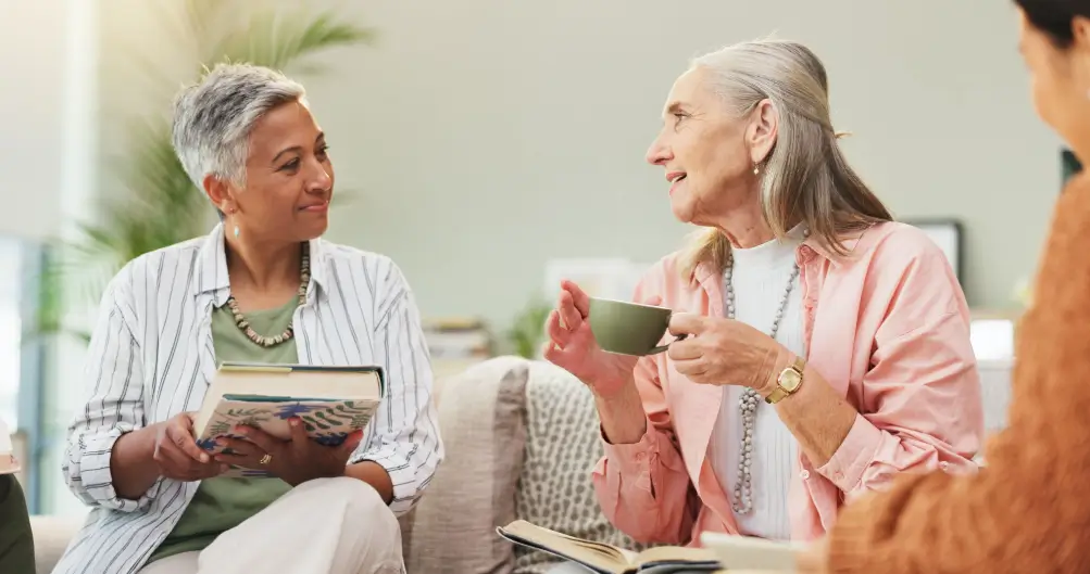 middle-aged woman reading her friend’s in-progress book over tea